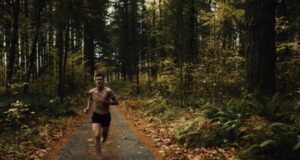 A topless male runner on a track through a forest