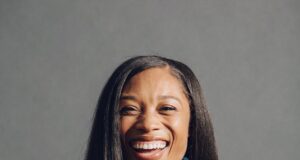 A smiling black woman wears multiple medals around her neck
