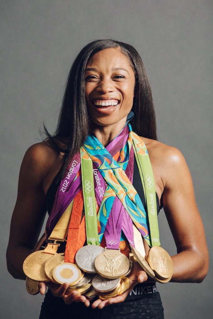 Allyson Felix A smiling black woman wears multiple medals around her neck