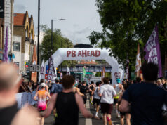 Record turnout at London’s biggest half marathon Runners on a London street. A gantry over the road reads PB Ahead