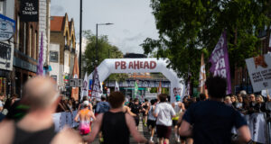 Runners on a London street. A gantry over the road reads PB Ahead