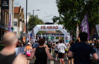 Record turnout at London’s biggest half marathon Runners on a London street. A gantry over the road reads PB Ahead