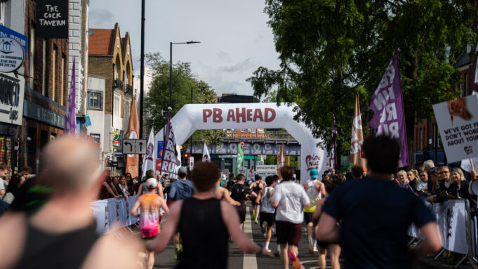 Hackney Half Runners on a London street. A gantry over the road reads PB Ahead