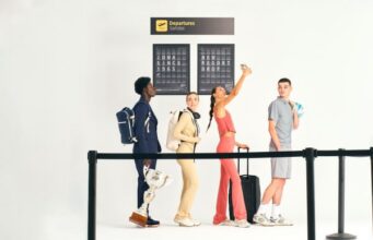 Joma’s Resort lifestyle collection two young men and two young women are dressed in different casual wear outfits. They look as though they're in a queue at an airport as have backpacks and luggage with them.
