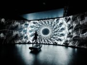 Psychedelic-inspired 24-Hour treadmill challenge A lone treadmill runner in front of a large screen showing a black and white kaleidoscopic image