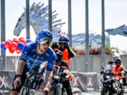 A triathlete on a bike with two support motorbikes behind hm