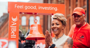 Short haired woman next to large bell.
