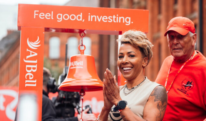 Short haired woman next to large bell.