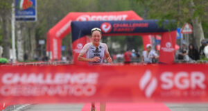 Female triathlete runs towards a red finish tape