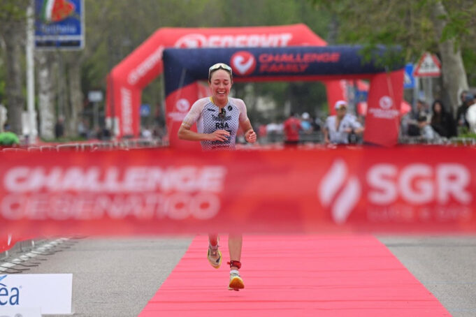 Female triathlete runs towards a red finish tape