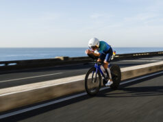 Woman rides low on a bike next to the sea