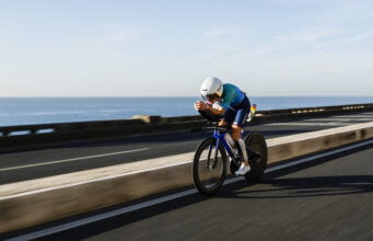 Woman rides low on a bike next to the sea