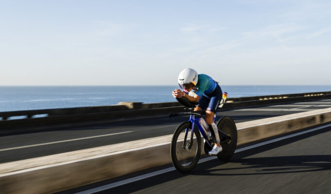 Woman rides low on a bike next to the sea