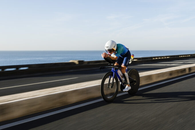 2025 IRONMAN 70.3 Cascais Portugal Lizzie Rayner Woman rides low on a bike next to the sea