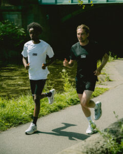 Two men running, one wears a white t-shirt and one wears a black one