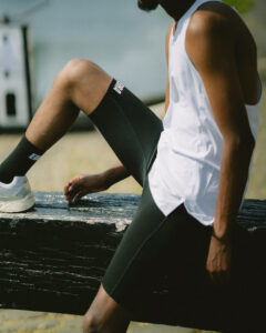Man wears a white singlet and black half tights