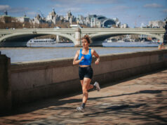 Woman in black shorts and blue crop top runs by the River Thames in central London