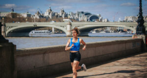 Woman in black shorts and blue crop top runs by the River Thames in central London