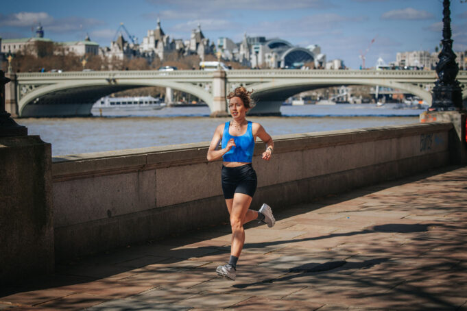 Esmée Gummer Woman in black shorts and blue crop top runs by the River Thames in central London