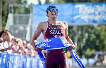 Hungary heroes shine at Tiszaujvaros World Cup Woman holds blue finish tape to abdomen and smiles