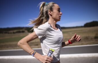 McColgan tackles gender gap in sports science Woman in white tshirt running along a road in what looks like a hot, sparse landscape. She's carrying a SiS gel