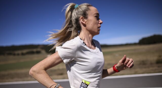 McColgan tackles gender gap in sports science Woman in white tshirt running along a road in what looks like a hot, sparse landscape. She's carrying a SiS gel