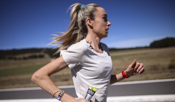 McColgan tackles gender gap in sports science Woman in white tshirt running along a road in what looks like a hot, sparse landscape. She's carrying a SiS gel