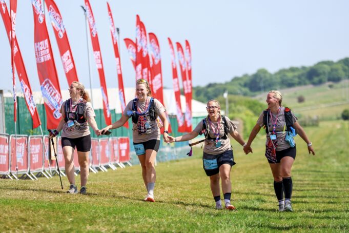L2B - Group Finish Holding Hands Smiling Group of four women finish a trail race holding hands and smiling