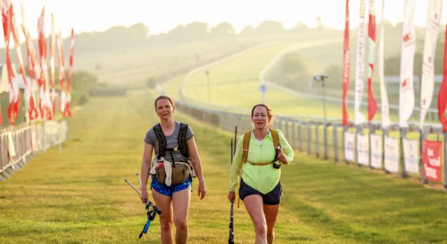 Thousands take on London to Brighton in heatwave Two female walkers on the finish straight. The sun is low in the sky