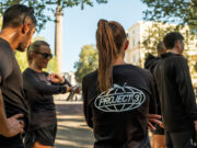 A group of people wearing black PUMA tshirts congregate on a street