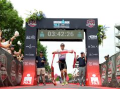 2026 IRONMAN 70.3 North American Championship Male triathlete runs under finish gantry holding red tape