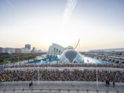 Realbuzz partners with Valencia Marathon Masses of runners on a road in front of a very futuristic looking white and blue building