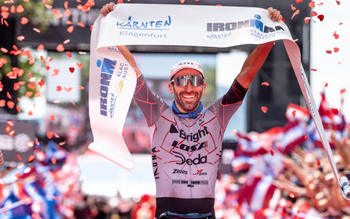 IRONMAN KLAGENFURT 2026 : ( PHOTO: Wouter Roosenboom Male triathlete in sunglasses liftes finish tape above head as confetti falls around him.