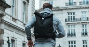 A man runs through a city past white buildings wearing a backpack