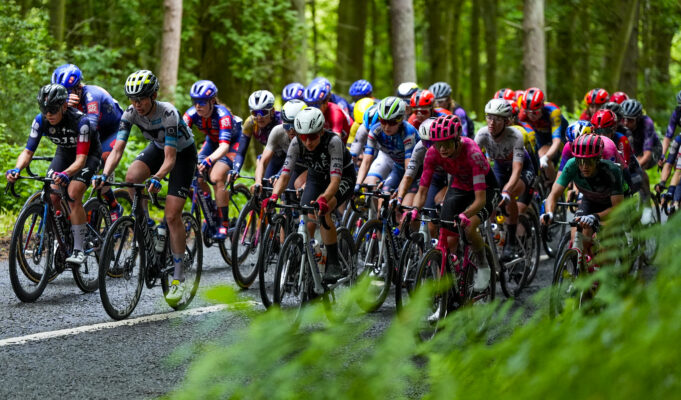 Peloton of female cyclists on a woodland road