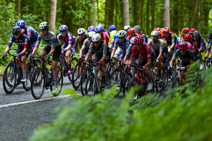 Peloton of female cyclists on a woodland road