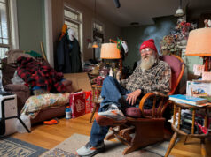 7 Things Every Runner Can Learn from Lazarus Lake An elderly man wering running shoes, jeans, plaid shirt and red beany hat sits in an armchair in a room full of stuff