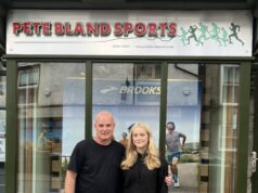 Cumbria’s rising fell runners awarded bursary A man and young woman stand in front of a shop front with Pete Bland Sports on the sign