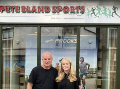 Cumbria’s rising fell runners awarded bursary A man and young woman stand in front of a shop front with Pete Bland Sports on the sign
