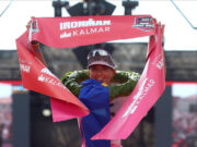 Philipp and Schomburg win IRONMAN Kalmar Triathlon Female triathlete grasps red finish tape above her head