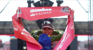 Female triathlete grasps red finish tape above her head