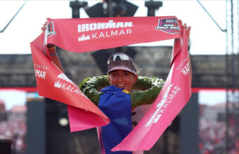 Female triathlete grasps red finish tape above her head