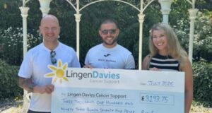 Two men and a woman hold a giant cheque