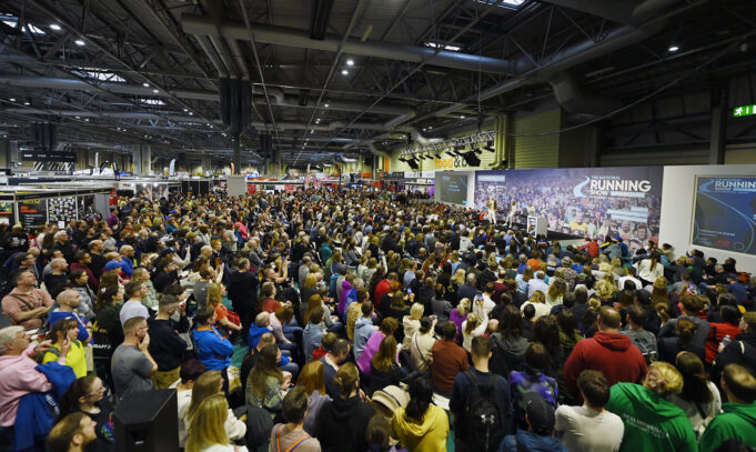 National Running Show Crowd Hundreds of people sit in front of a large stage listening to a speaker