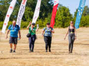 Records tumble at Surrey Hills ultra 4 people walk across a field lined with colourful advertising flags