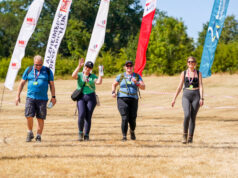 Records tumble at Surrey Hills ultra 4 people walk across a field lined with colourful advertising flags