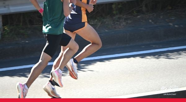 Road race Two male athletes in shorts and vest run on a road. Their heads are not visible.