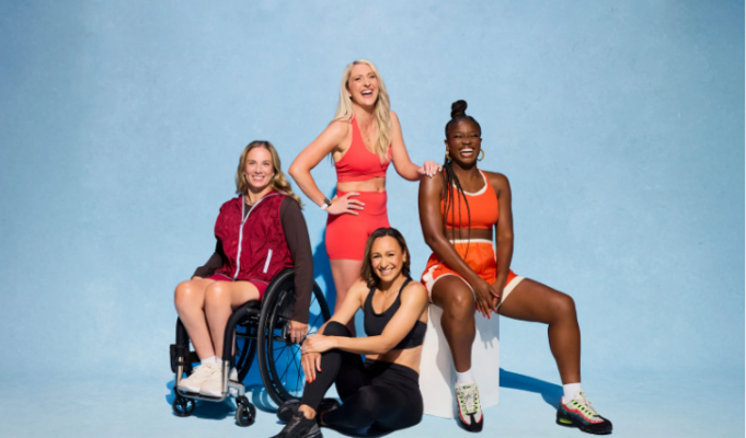 4 women pose for a photo in theiir sports kit. One woman is in a wheelchair.