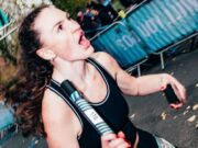 Calling London’s running clubs Woman wearing black vest and holding a relay baton runs past the camera. Her mouth is open in what appears to be a shout to a fellow team ember out of shot