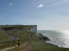 Runners on the edge of dramatic white chalk cliffs. The sea is to the right.